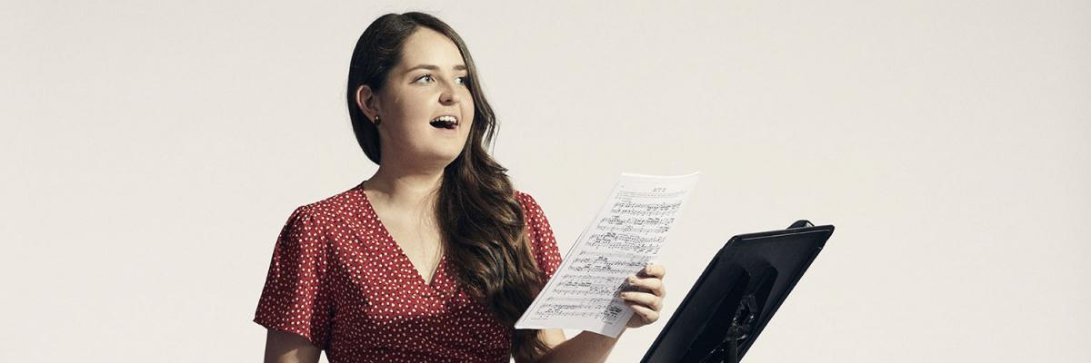 Student singing while holding sheet music
