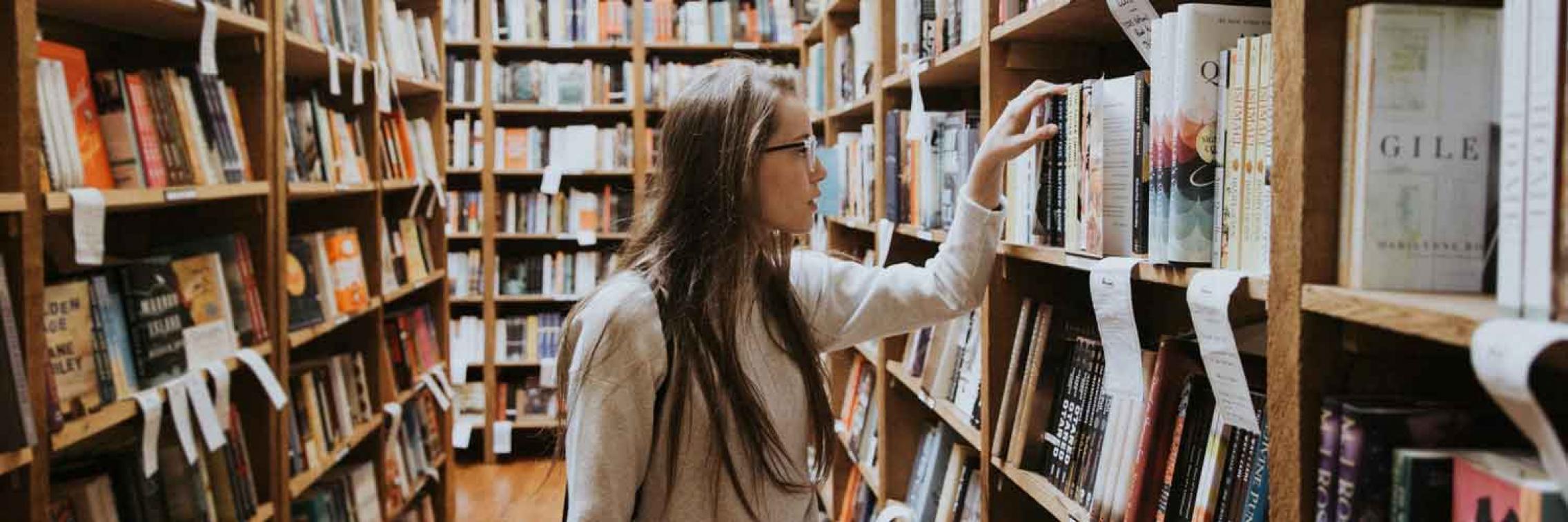 Lady with long hair, searching for books in a bookstore
