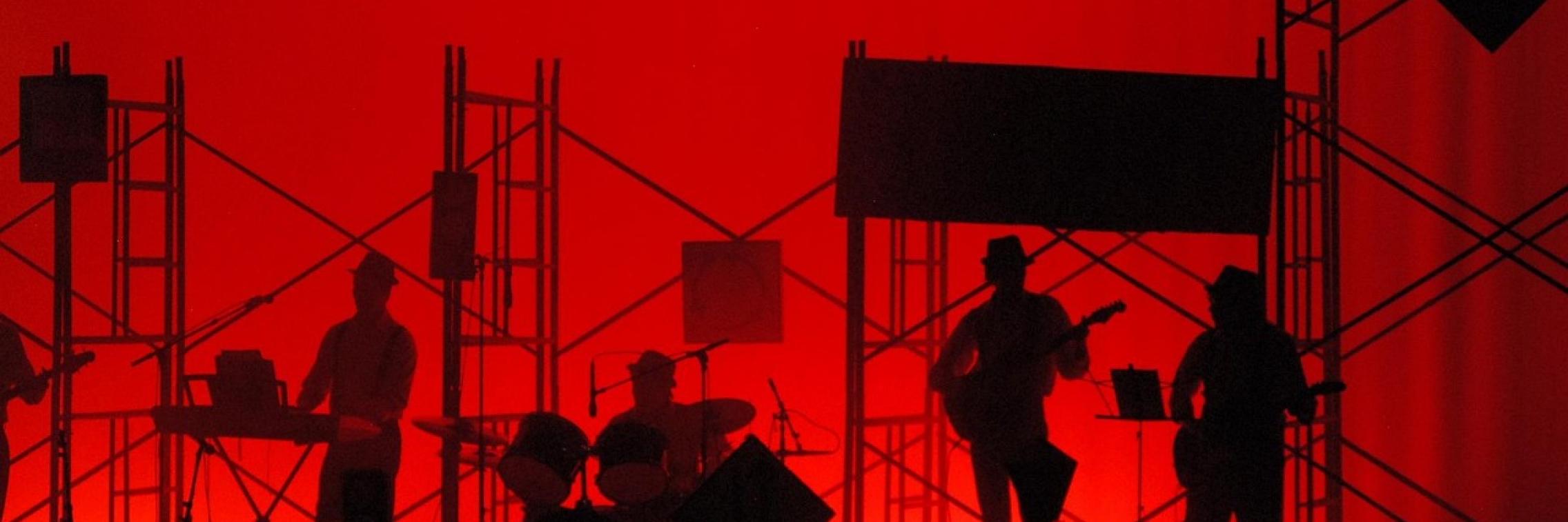 Musicians perform on a red-lit stage.