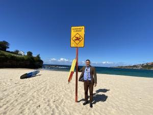 Dr Masaki Shibata stands with a safety sign at a beach