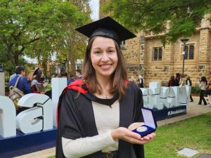 Jessica Pohlmann on her graduation day, holding her Masters by Research Medal