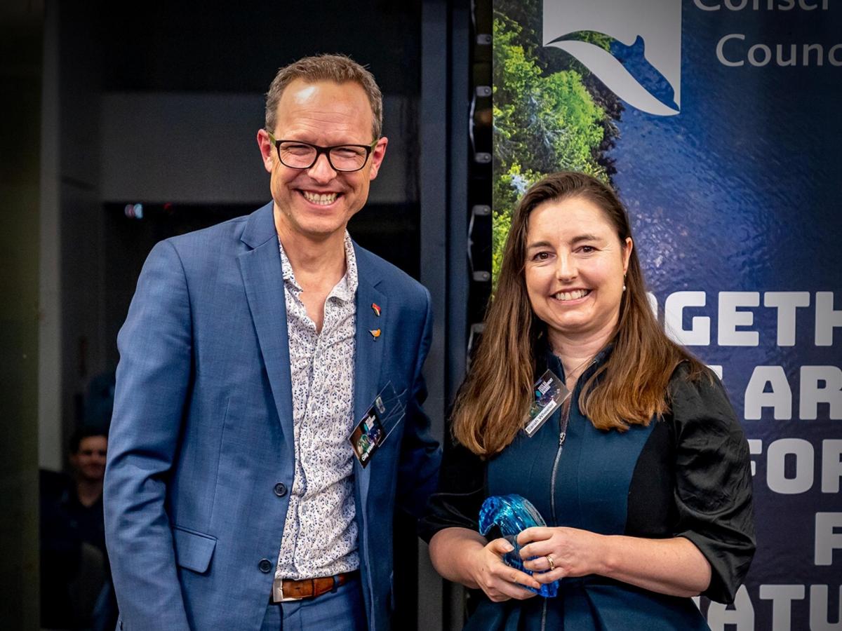 Sarah Wheeler smiles and holds her Jill Hudson Award for Environmental Protection