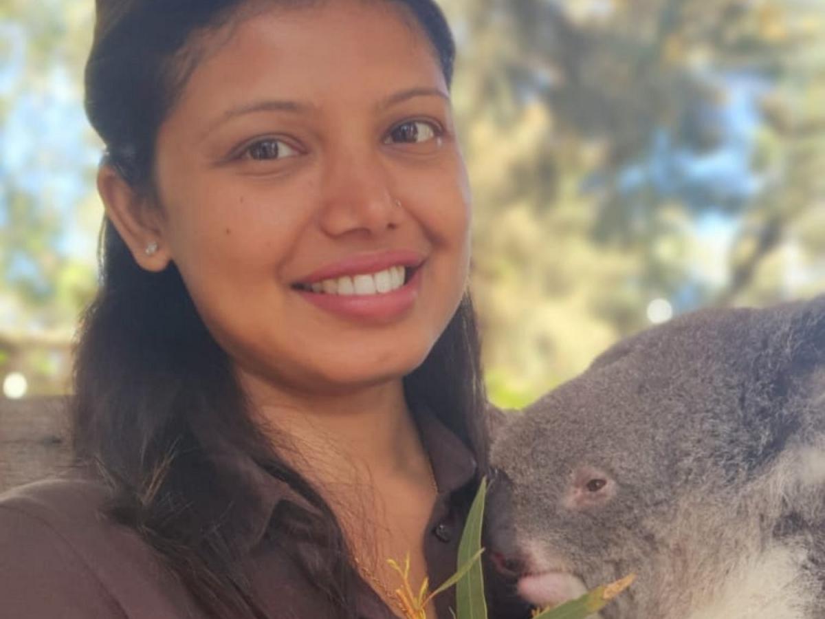 Simrin Kafle smiles and holds a koala