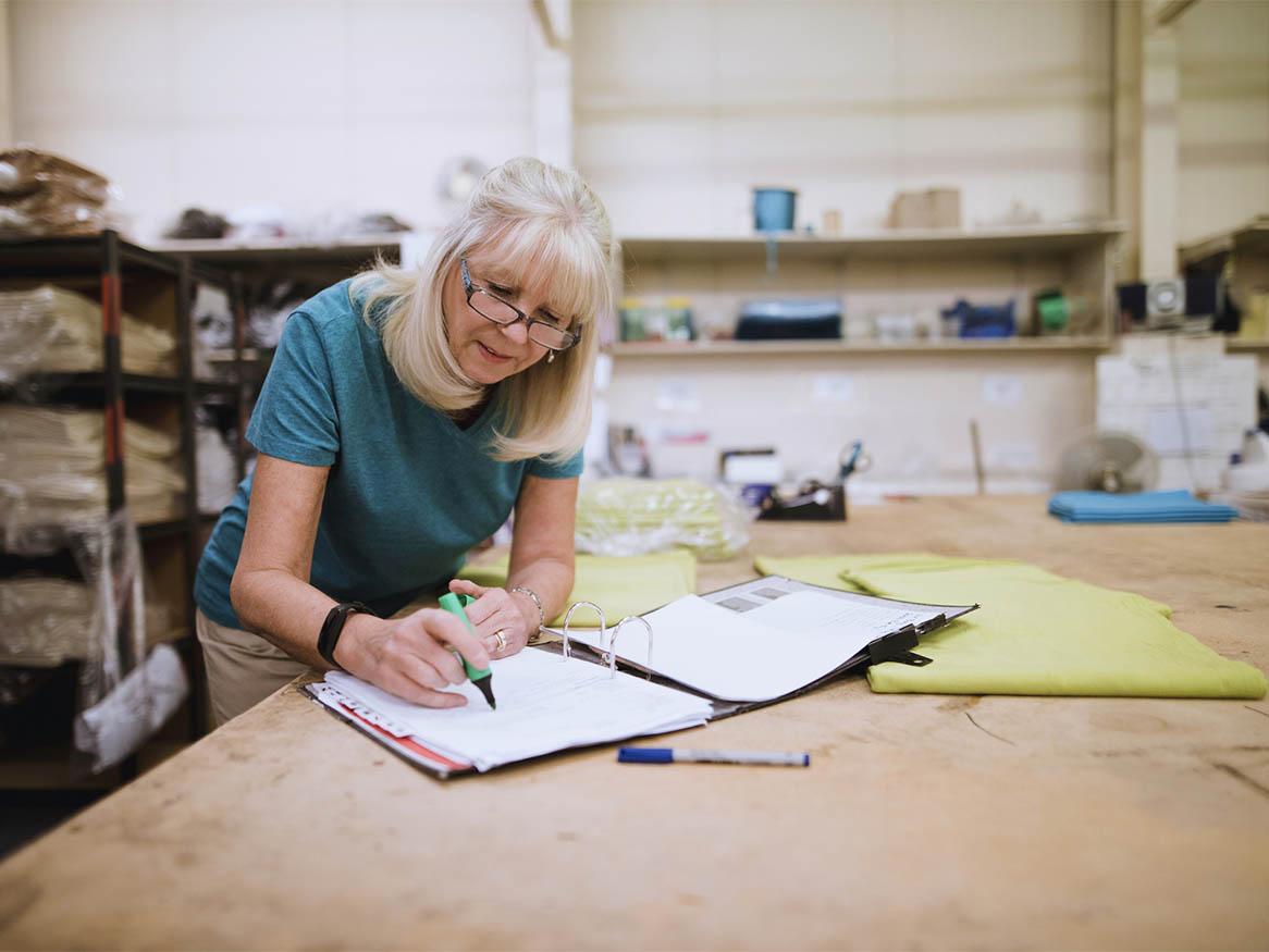 An older worker marking text in a binder