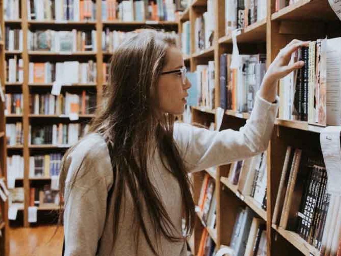 Lady with long hair, searching for books in a bookstore