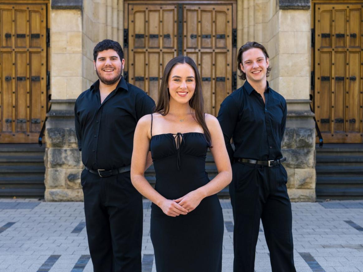 Music Theatre students Brendan, Amy, and Sascha stand in front of Bonython Hall and smile