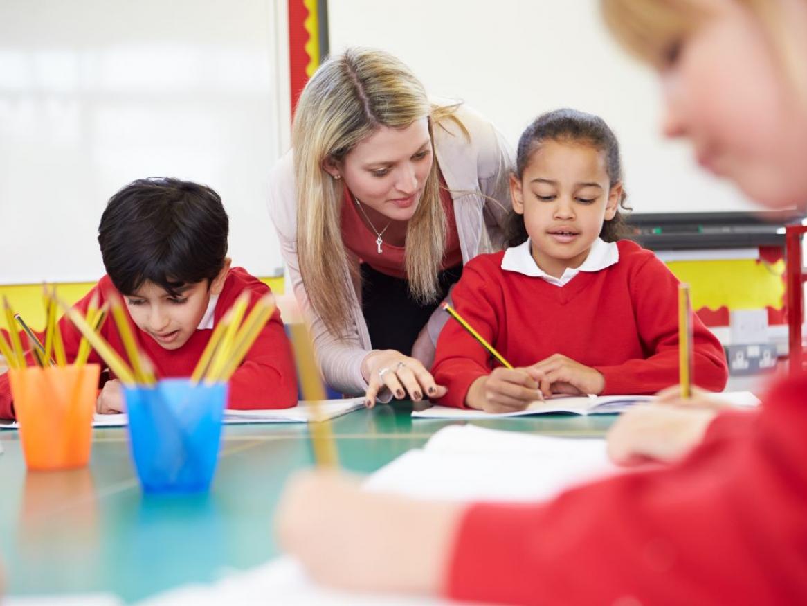 A teacher helps young students