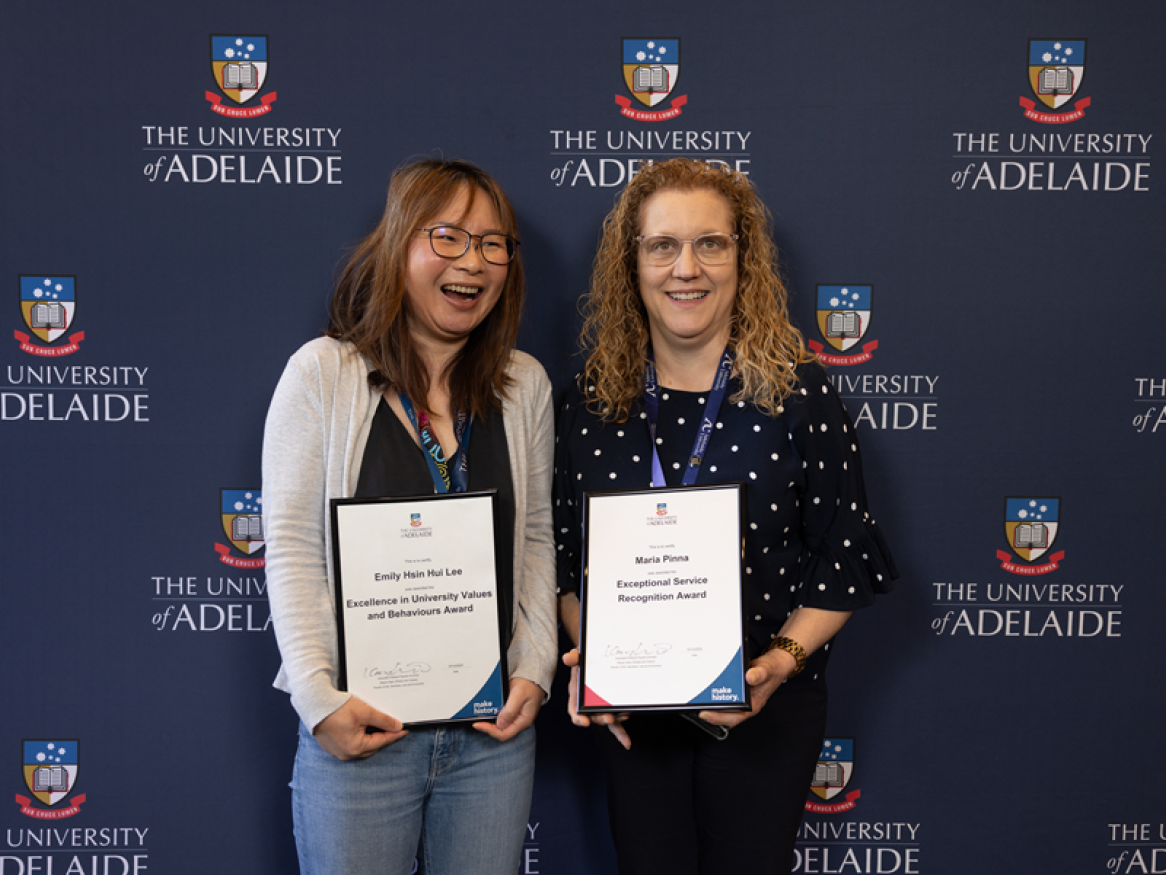 Emily and Maria smile and hold their awards