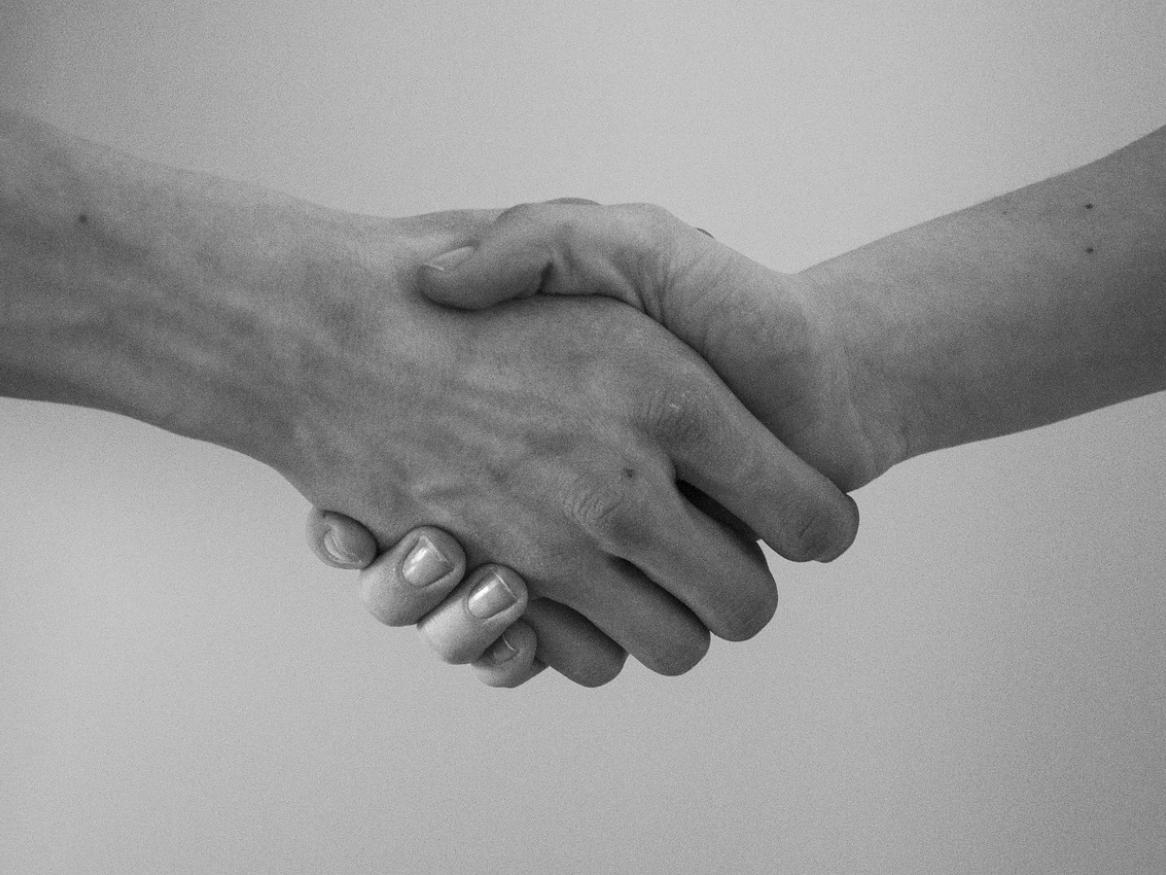 Two hands join in a handshake in a black and white image