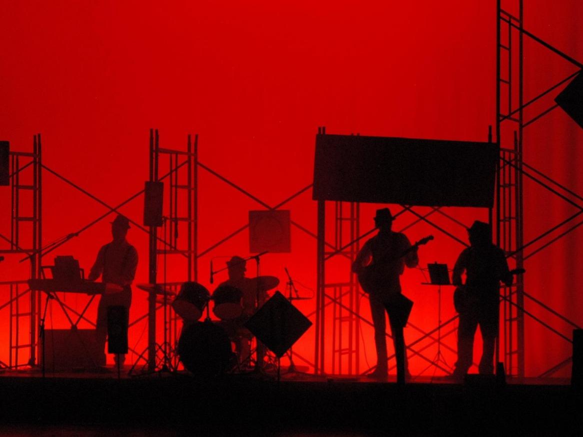 Musicians perform on a red-lit stage.