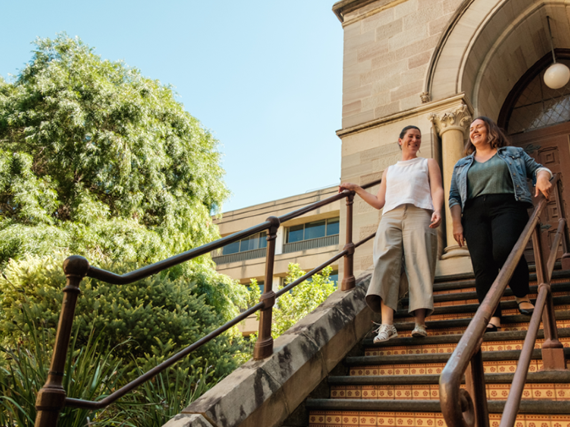 Two female students walk down the stairs at Elder Hall