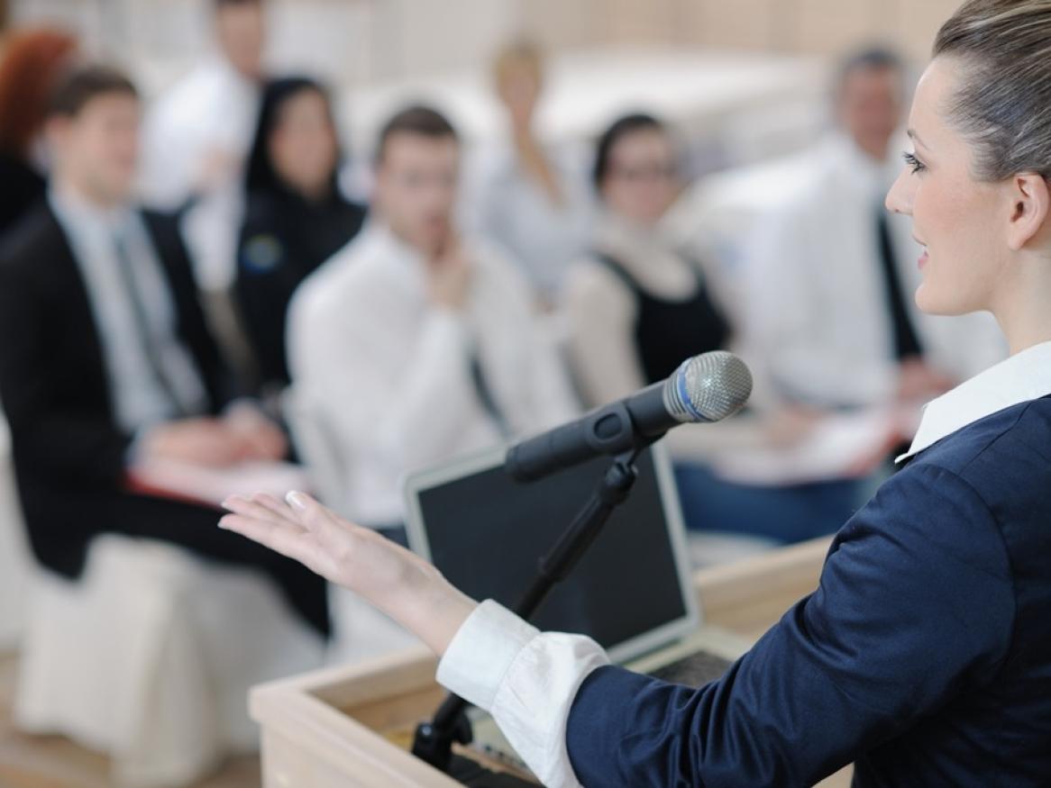 A woman speaks in front of a crowd